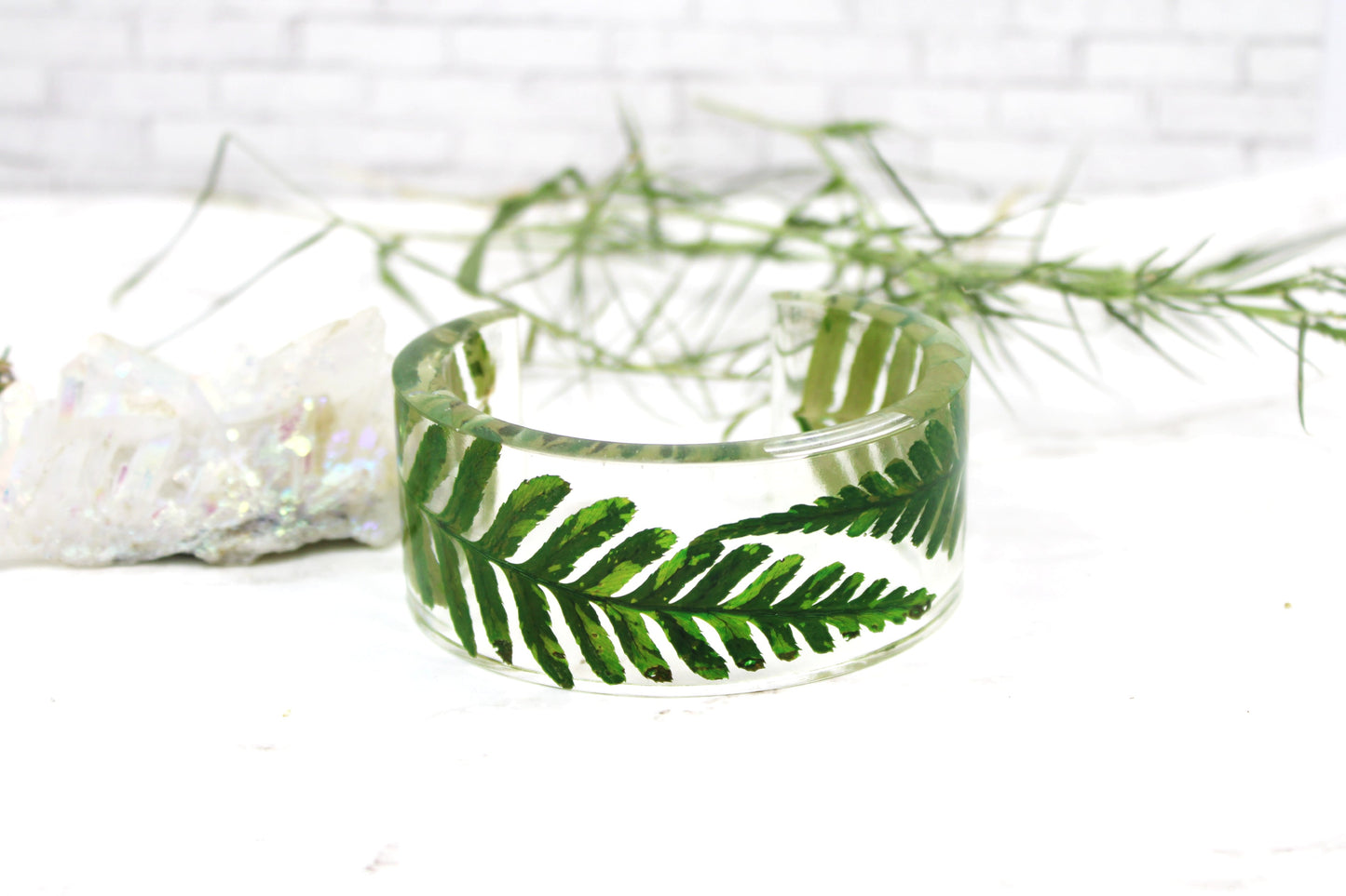 Clear bracelet with real dry green fern on a white background