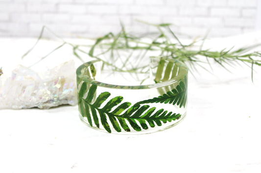 Clear bracelet with real dry green fern on a white background