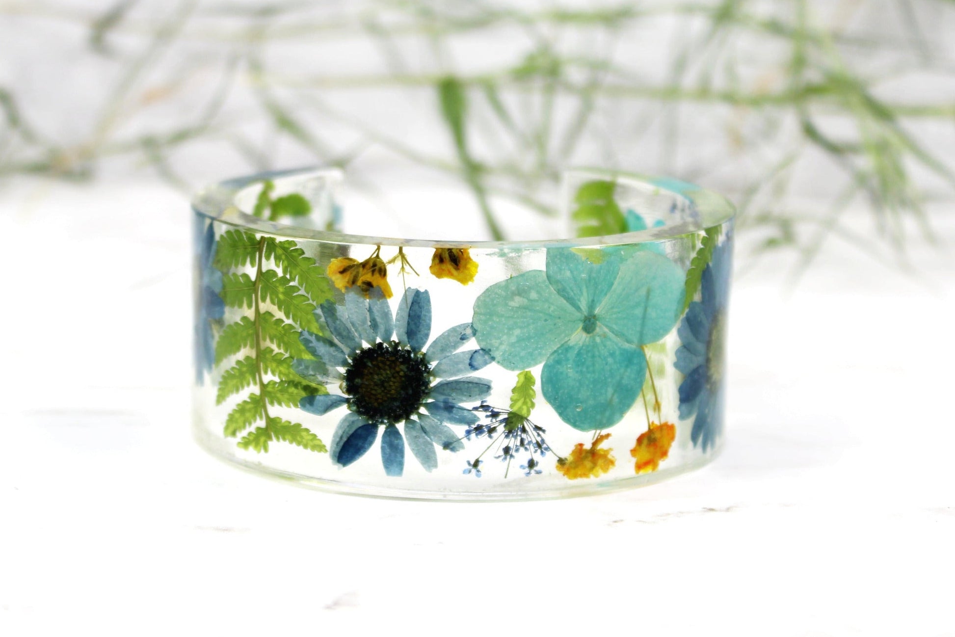 Resin ring with blue and green floral design on a white background