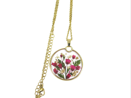 Gold necklace with a round pendant featuring pressed flowers on a white background